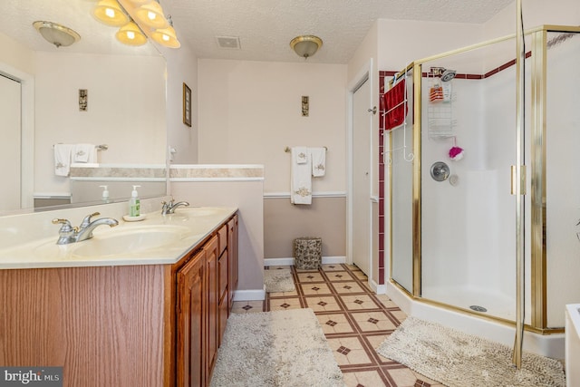 bathroom with a stall shower, double vanity, a sink, and tile patterned floors