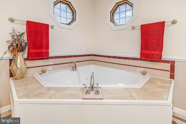 full bathroom with baseboards, plenty of natural light, and a tub with jets