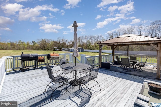 deck featuring an outbuilding, a gazebo, outdoor dining area, and a storage unit