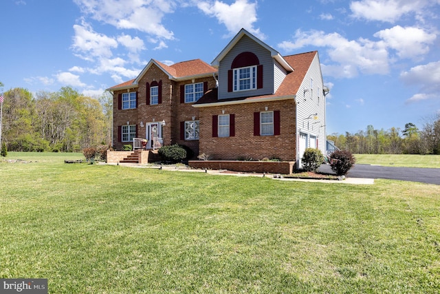 view of front of property featuring a garage, a front yard, and brick siding