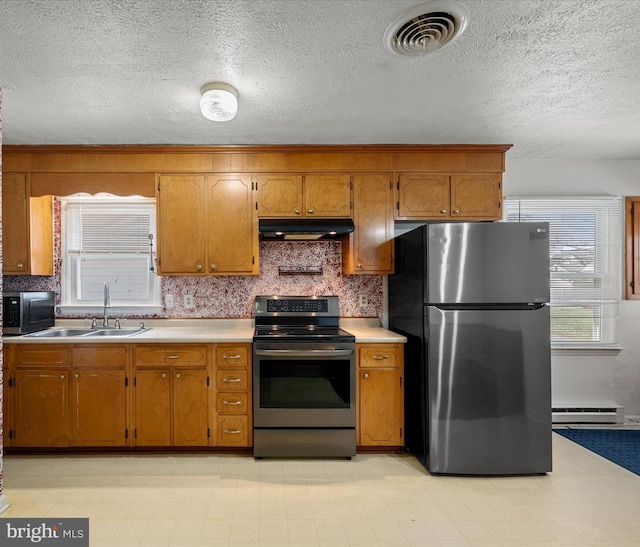 kitchen with a sink, appliances with stainless steel finishes, light countertops, under cabinet range hood, and visible vents