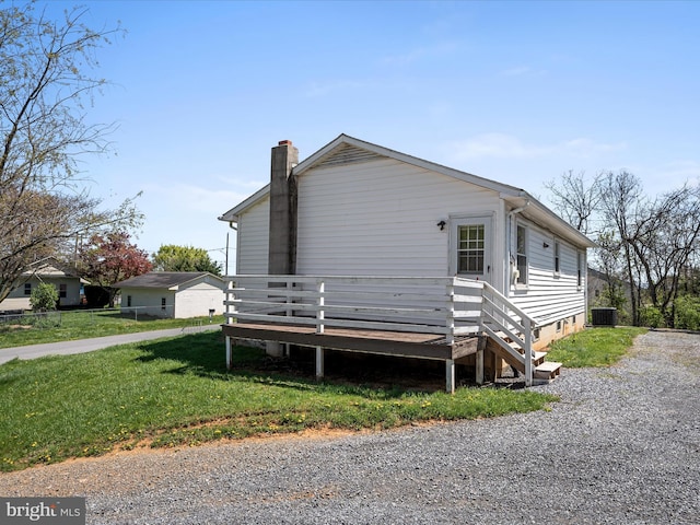 view of property exterior with a wooden deck, a chimney, a yard, and cooling unit