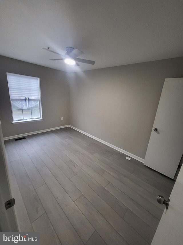 spare room with visible vents, ceiling fan, baseboards, and dark wood finished floors
