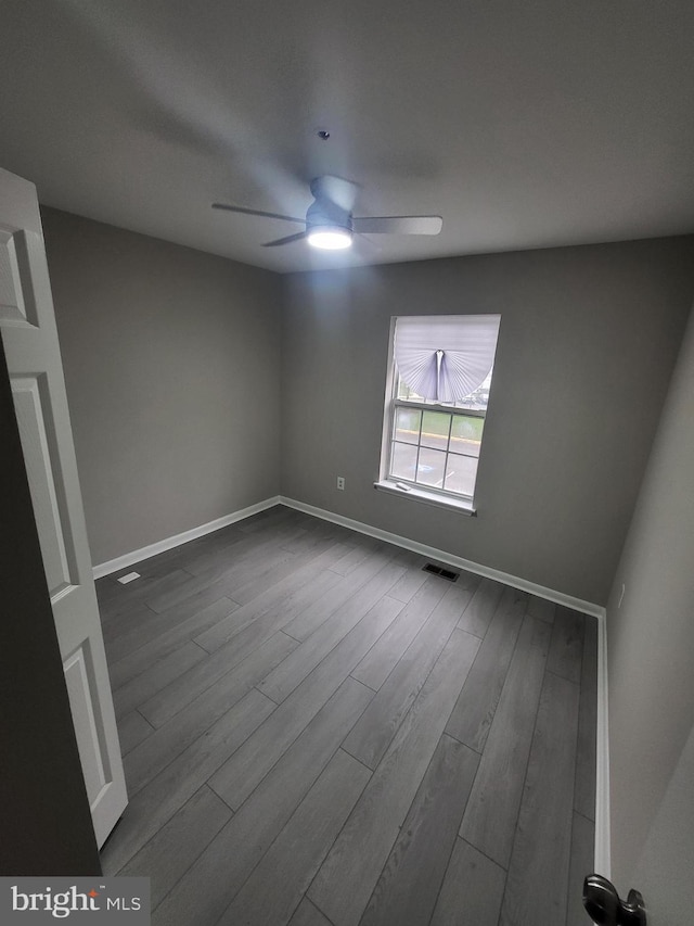 spare room with visible vents, baseboards, a ceiling fan, and dark wood finished floors