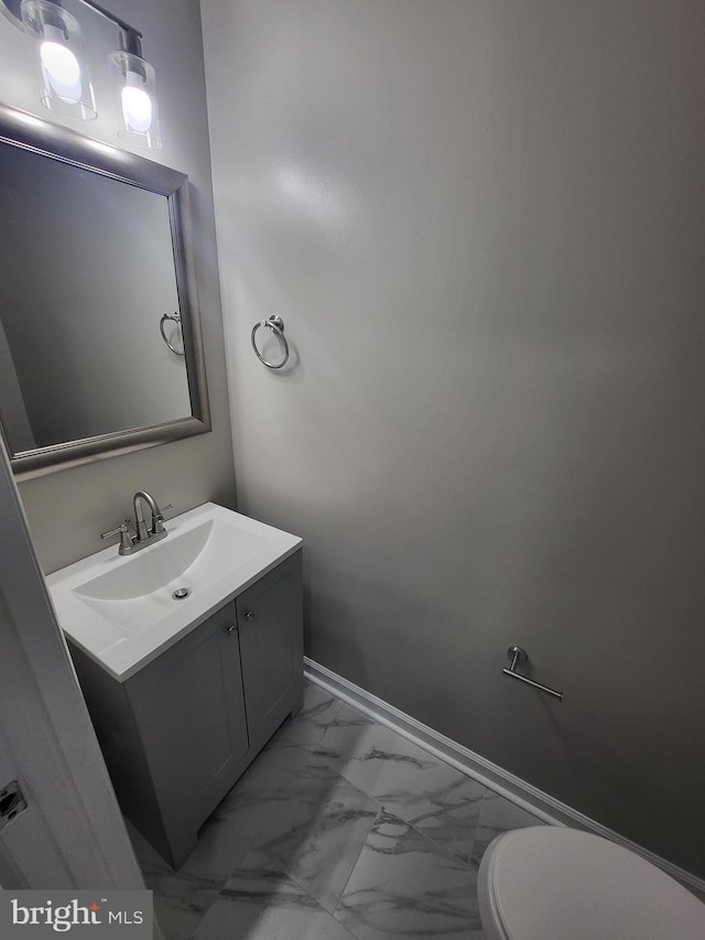 half bath with vanity, marble finish floor, baseboards, and toilet
