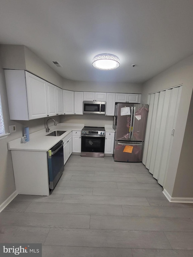 kitchen with visible vents, a sink, light countertops, stainless steel appliances, and light wood-style flooring