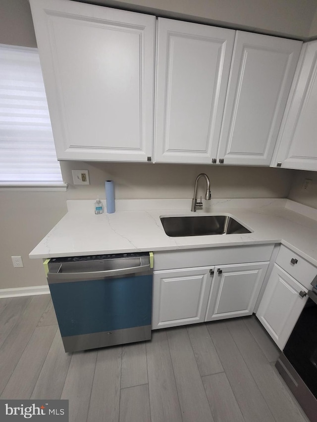 kitchen featuring dishwashing machine, white cabinetry, a sink, and wood finished floors