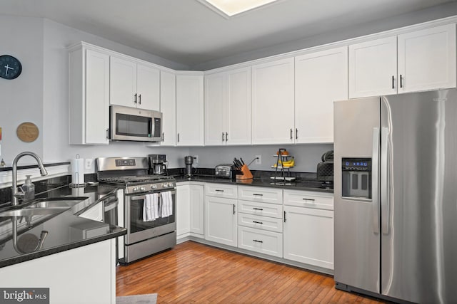 2068 Capstone, Herndon, VA 20170 - kitchen with stainless steel appliances, a sink, white cabinetry, light wood-type flooring, and dark stone countertops