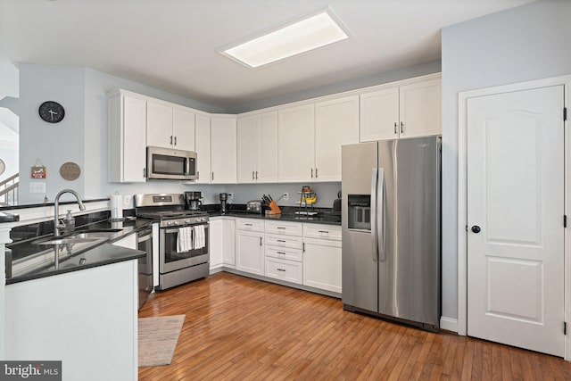 2068 Capstone, Herndon, VA 20170 - kitchen with stainless steel appliances, a sink, dark countertops, white cabinetry, and light wood finished floors