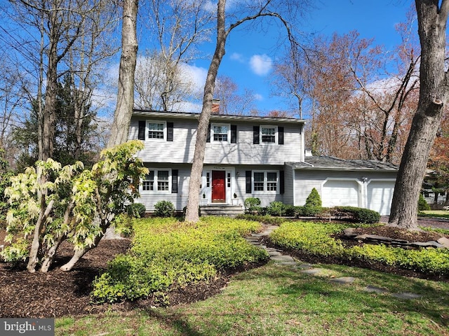 colonial house featuring a chimney and an attached garage