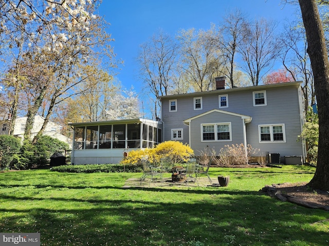 back of property with a chimney, central AC, a yard, and a sunroom