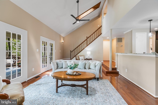 living area with visible vents, baseboards, wood finished floors, a ceiling fan, and stairs
