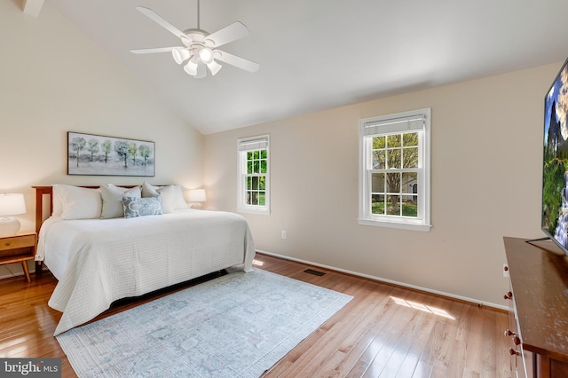 bedroom with ceiling fan, wood finished floors, visible vents, baseboards, and lofted ceiling