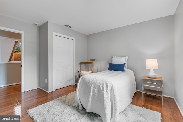 bedroom with baseboards, visible vents, and wood finished floors