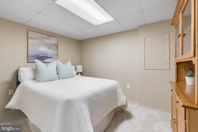 bedroom featuring a paneled ceiling, light carpet, and baseboards