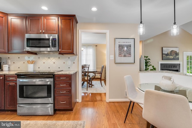 kitchen with pendant lighting, decorative backsplash, light wood-style floors, stainless steel appliances, and baseboards