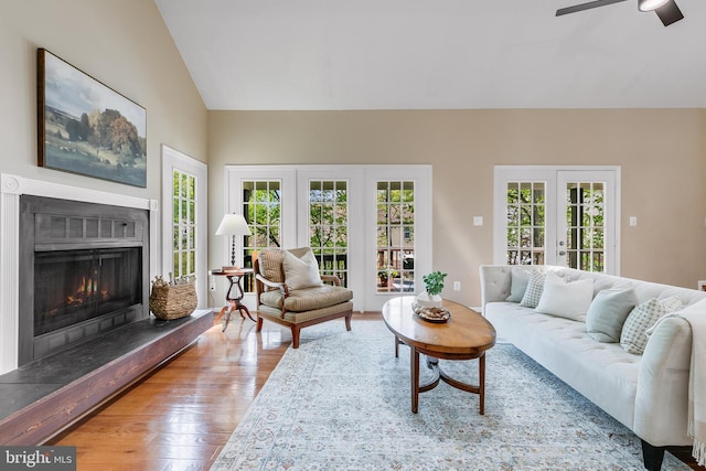 living room with a ceiling fan, wood finished floors, a healthy amount of sunlight, and vaulted ceiling