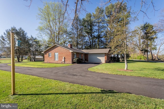 single story home featuring a chimney, driveway, a front yard, brick siding, and a garage
