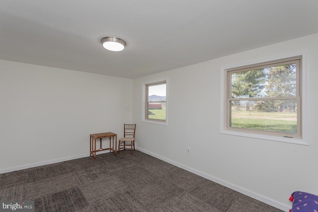 empty room with plenty of natural light, baseboards, and dark carpet