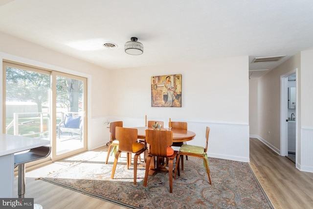 dining space with visible vents, a wainscoted wall, and wood finished floors