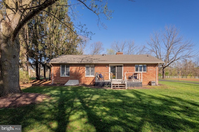 back of house featuring a chimney, a lawn, a wooden deck, and brick siding