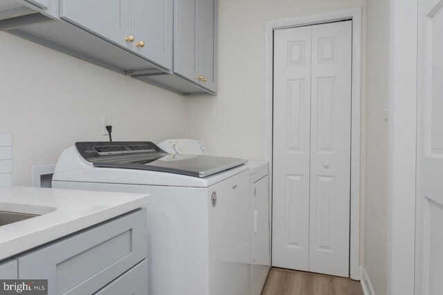 laundry area featuring washer and dryer, light wood-type flooring, and cabinet space