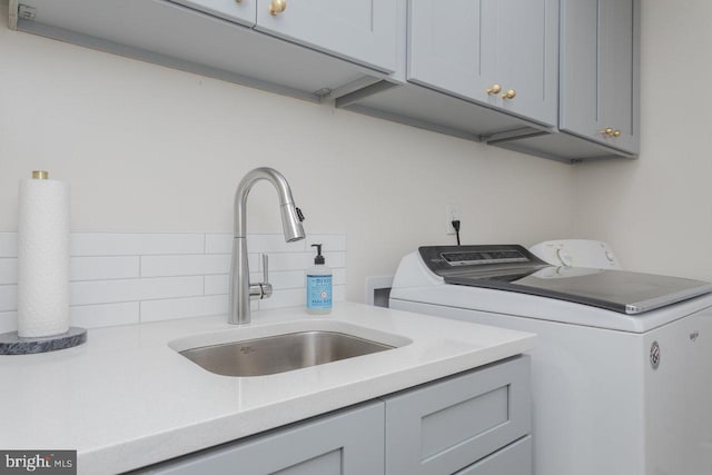 laundry room with washer and dryer, a sink, and cabinet space