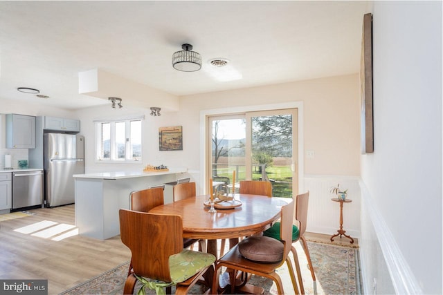 dining area with visible vents, wainscoting, and light wood-style floors