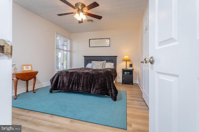 bedroom with baseboards, ceiling fan, light wood-style floors, and a fireplace