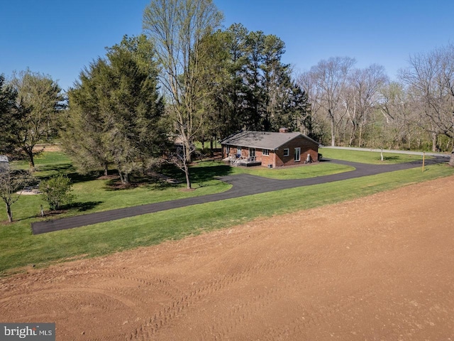 view of property's community featuring aphalt driveway and a lawn