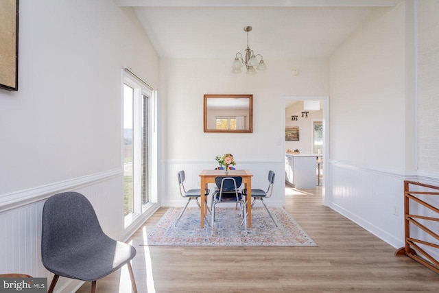 dining space with wainscoting, an inviting chandelier, and wood finished floors