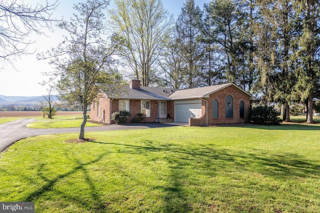 single story home featuring a chimney, driveway, a front lawn, brick siding, and a garage