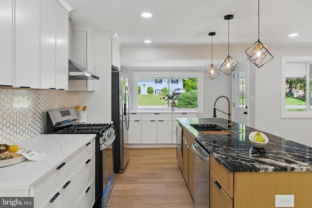 4838 Randolph Dr, Annandale, VA 22003 - kitchen featuring decorative backsplash, light wood-style floors, wall chimney range hood, a sink, and appliances with stainless steel finishes