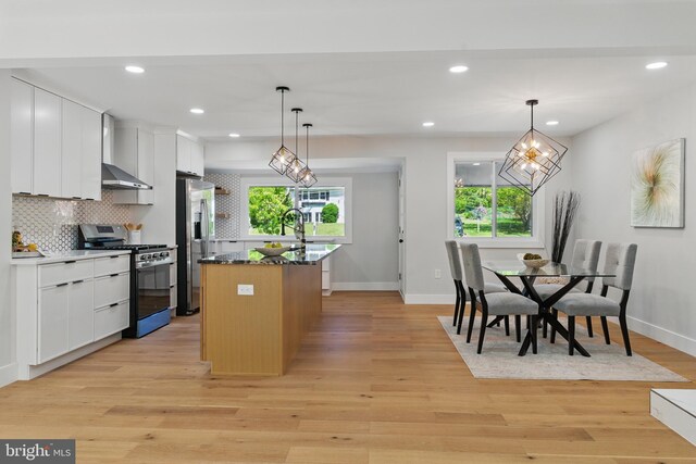 4838 Randolph Dr, Annandale, VA 22003 - kitchen with light wood-style floors, a center island with sink, wall chimney range hood, tasteful backsplash, and stainless steel appliances