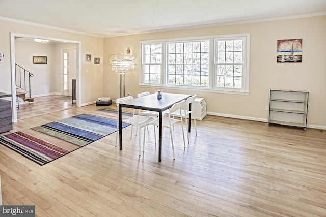 dining area featuring ornamental molding, baseboards, stairway, and wood finished floors