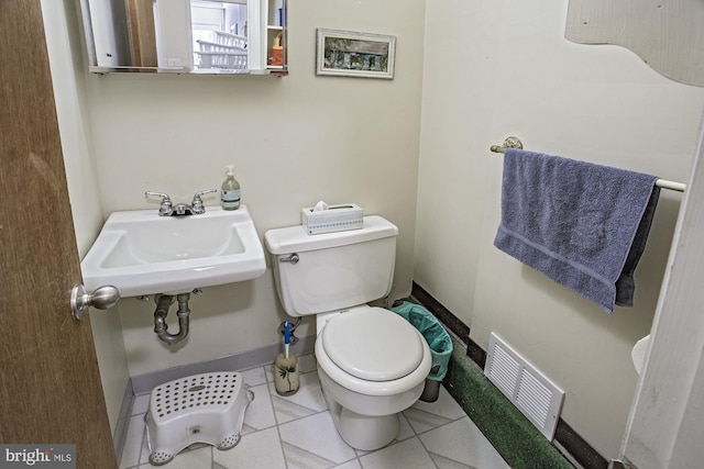 bathroom with toilet, a sink, tile patterned flooring, and visible vents