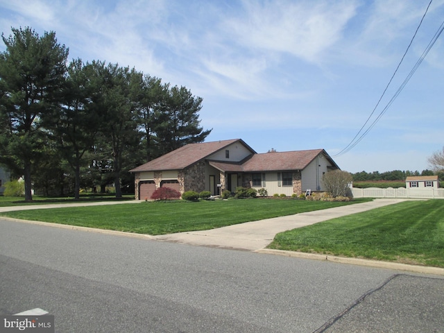 view of front facade featuring an attached garage, a front yard, concrete driveway, and fence