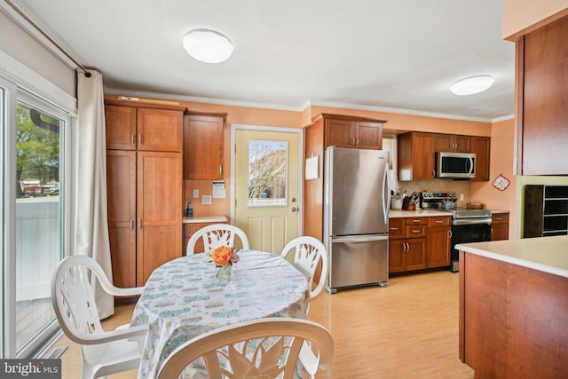 205 S Lehigh Rd, Glassboro, NJ 08028 - kitchen featuring tasteful backsplash, stainless steel appliances, light countertops, ornamental molding, and brown cabinetry
