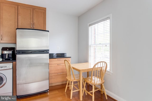 kitchen featuring light wood-type flooring, freestanding refrigerator, a wealth of natural light, and washer / clothes dryer