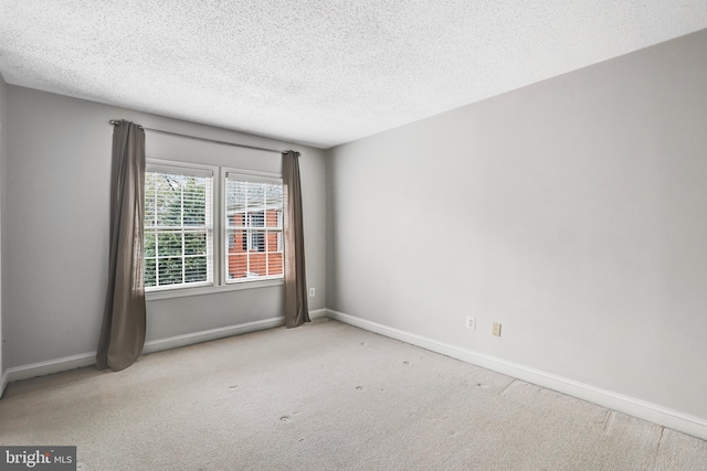 carpeted spare room featuring baseboards and a textured ceiling