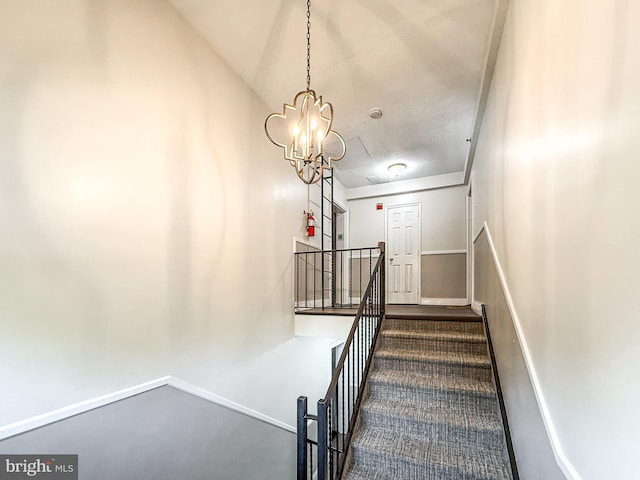 staircase featuring carpet floors, lofted ceiling, and a chandelier