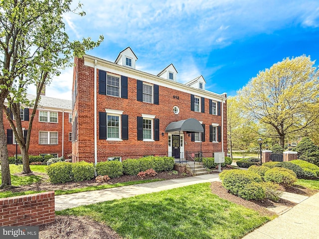 multi unit property with brick siding and a front yard