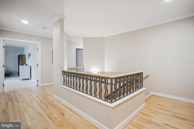 hallway featuring wood finished floors, baseboards, an upstairs landing, and crown molding