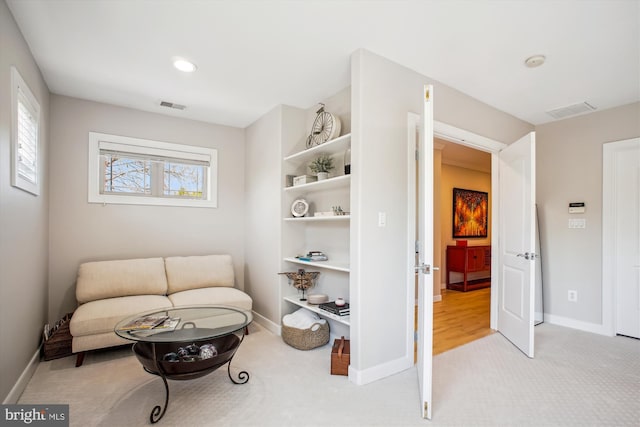 living area with baseboards, visible vents, and carpet floors