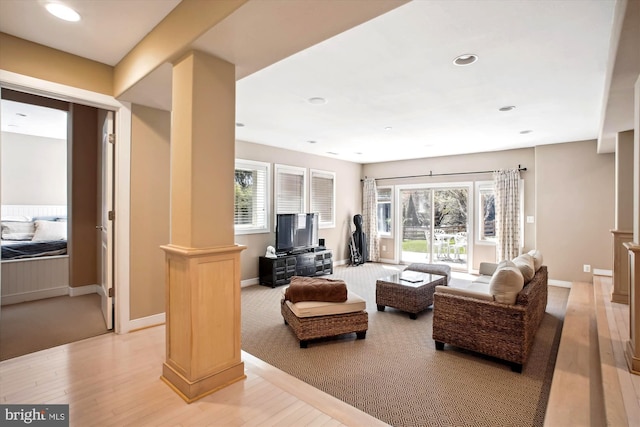 living room with light wood-type flooring, plenty of natural light, and decorative columns