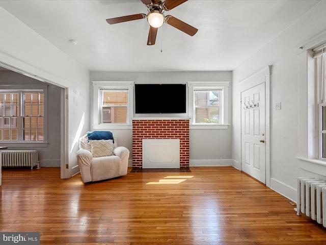 interior space featuring radiator, wood-type flooring, a ceiling fan, and baseboards