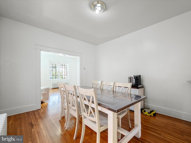 dining space featuring hardwood / wood-style flooring, baseboards, and radiator