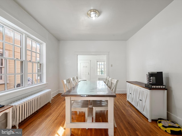 dining space featuring radiator heating unit, baseboards, and wood finished floors
