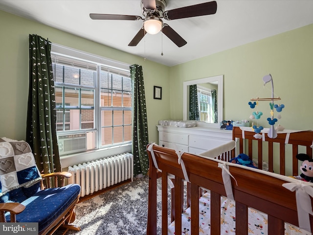 bedroom featuring a ceiling fan, radiator heating unit, multiple windows, and cooling unit