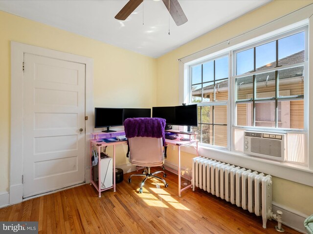 office space with radiator heating unit, a wealth of natural light, a ceiling fan, and wood finished floors